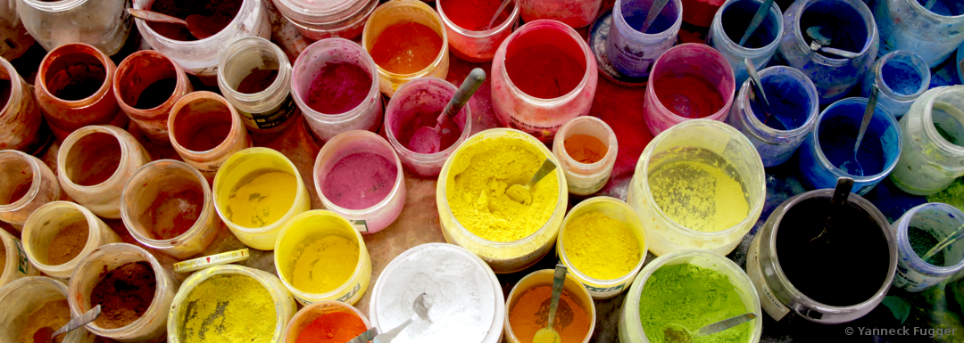 Bunte Pigmenttöpfe mit knalligen Farben stehen eng aneinandergereiht