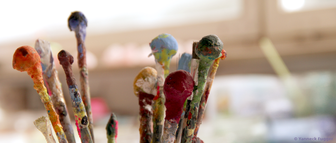 Alte Pinsel mit trockenen Farbresten sind dekorativ aufgestellt
