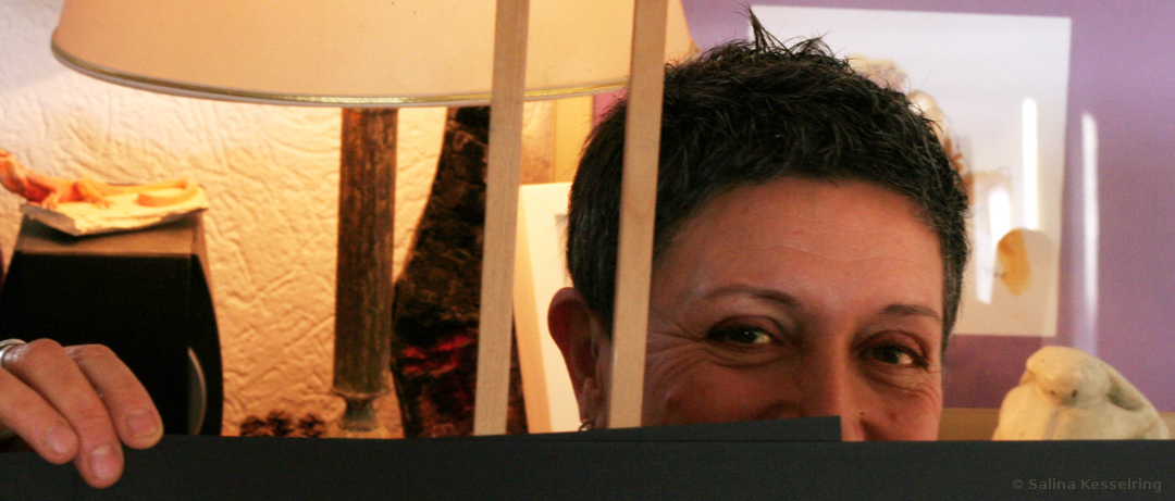 Maryse schaut hinter einer Mappe hervor